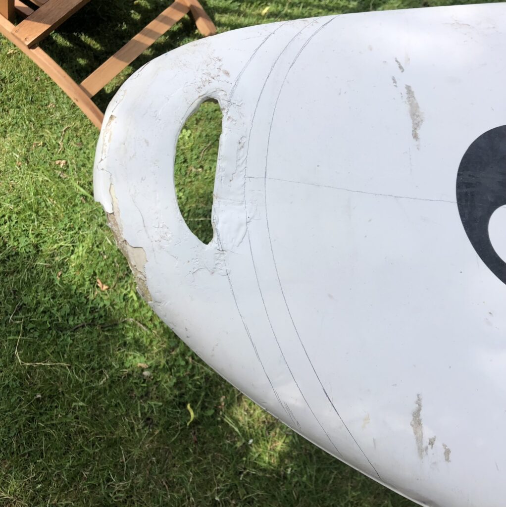 Auf dem beschädigten Surfboard wird das neue Shape mit zusätzlichen Linien zum Verrunden angezeichnet.